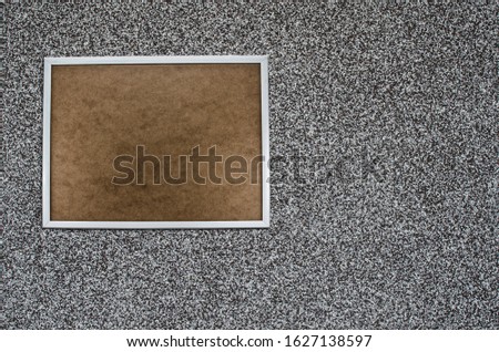 Wooden brown board with white boarder with space for text hanging on gray granite wall. Empty cork board with copy space with wooden white frame. Notice board. Gray granite texture.Wall banner, grunge