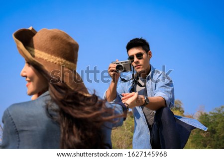 men take pictures for women and hold her hand with blue sky background young asian couple travel tourist tracking in the nature forest concept