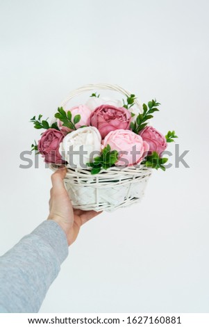 Flowers in bloom: A bouquet of pink and white peonies in a bascket in a male hand.