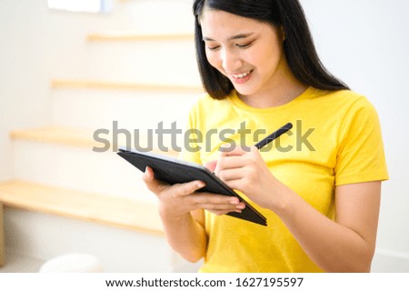 Young Thai lady entrepreneur using innovation technology on tablet for selling online and home delivery. Startup SME business and work at home concept