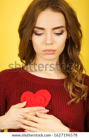 Photo of pretty woman holding little heart near breast expressing cardiology safety concept isolated yellow color background