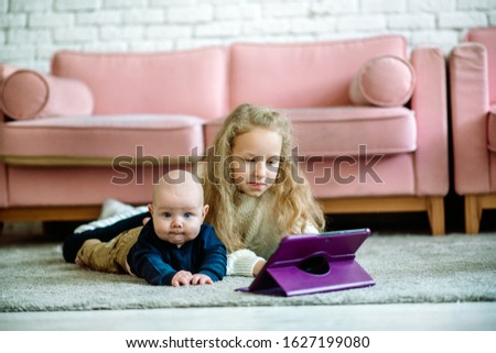 .Brother and sister are watching cartoon on laptop while lying on floor.friendly enthusiastic smart little children. Children and social addiction. The concept of family love, care and education.