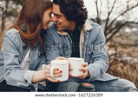 gentle and stylish couple sitting in the autumn park and drinking a tea