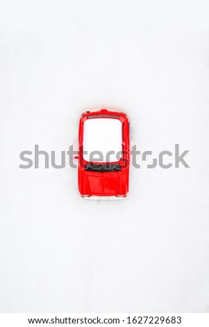 Top view of red car and white hood on the snow. Vertical photo. Winter vacation