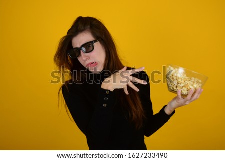 displeased woman with popcorn in hands on an isolated yellow background