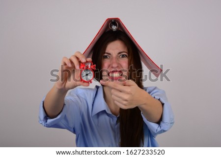 angry woman in a shirt with an alarm clock in the hands of emotions