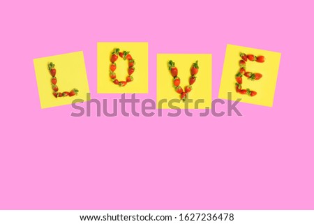 Strawberry letters with the word Love on a pink background. Valentine's Day, Women's Day or Mother's Day. Top view, copy space.