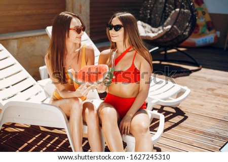 Girls near a pool. Friends in a stylish swimsuits. Ladies on a summer vacation