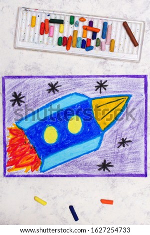Photo of colorful drawing: blue space rocket in cosmos 
