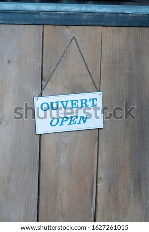 closeup of panel with text Open Ouvert in french and in english on wooden shop door
