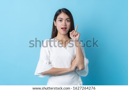 happy asian young woman in white fashion dress getting an ideas isolated on blue background.
