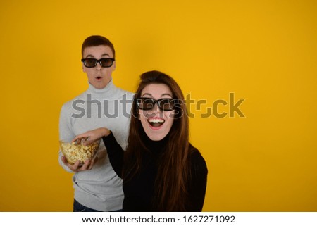 man and woman enthusiastically watch a movie and eat popcorn