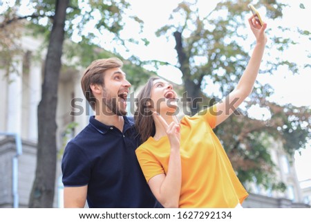 Beautiful lovely young couple walking at the city streets, taking a selfie.