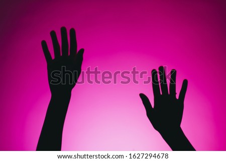 silhouette of female hands isolated on a pink background. abstraction