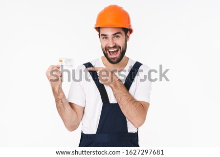 Image of happy emotional young man builder in helmet isolated over white wall background holding credit card pointing.
