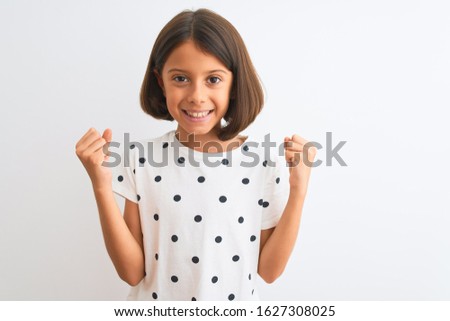 Young beautiful child girl wearing casual t-shirt standing over isolated white background celebrating surprised and amazed for success with arms raised and open eyes. Winner concept.