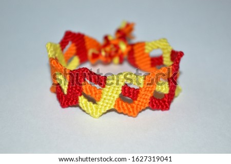 Designer exclusive colorful  friendship bracelet with fiery colors of handmade of embroidery bright floss and thread with knots isolated on white background