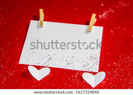 Composition for Valentine's Day.  Clothespins, hearts and paper for note against a red background. Elements to use in design or card.
