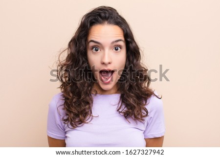 young pretty woman looking very shocked or surprised, staring with open mouth saying wow