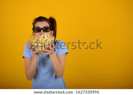 woman in blue t-shirt with popcorn on a yellow background relax