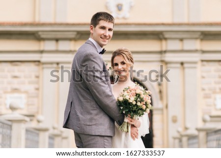 Beautiful elegant couple of newlyweds in love on the background of an old building and paving stones, European wedding