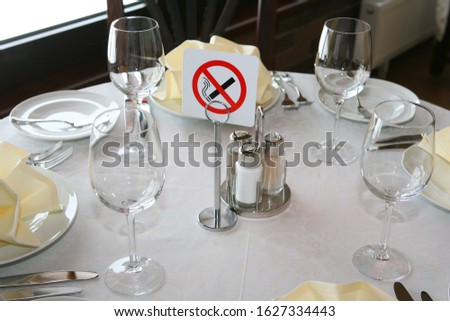 A fragment of table setting for four with a sign prohibiting smoking.
