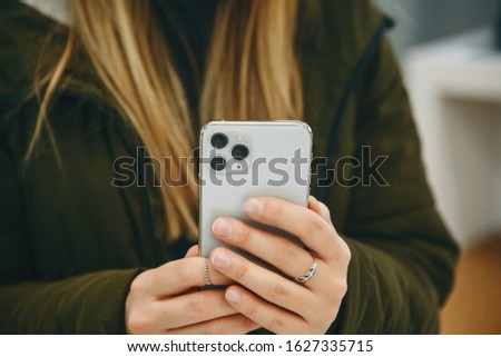 The girl uses a new cell phone with a triple camera.