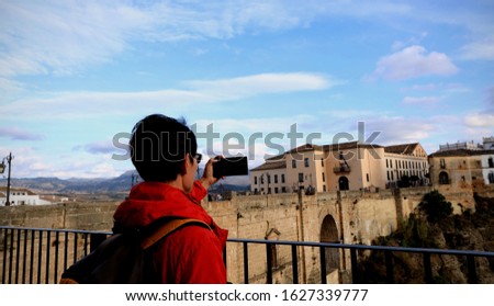 Tourist man which he is a  hands holding take a picture by smartphone view of Ronda city in Spain at Puente Nuevo Bridge