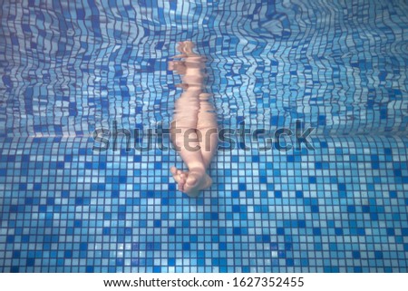 Little girl feet under water in swimming pool. Legs on the swimming pool.