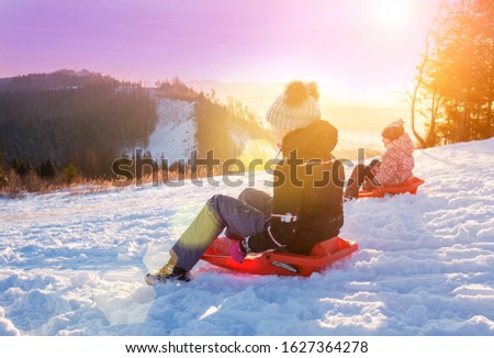 Children ride from a snow slide, have fun, play. Happy winter holidays.