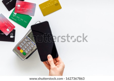 Contactless payment, NFC technology. Hand hold phone near terminal on white background top-down copy space