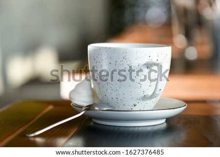 Tea cup with black tea on a small little plate with white tea pot on dark wooden table. Food photography. Restaurant or cafe concept.
