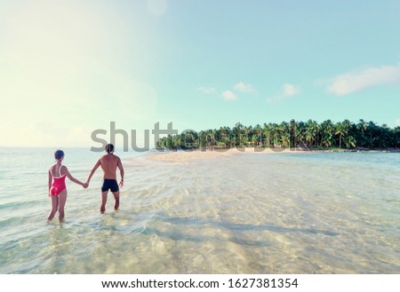 Honey moon on the sea shore. Back view of loving couple walking together on beautiful tropical white sand beach.