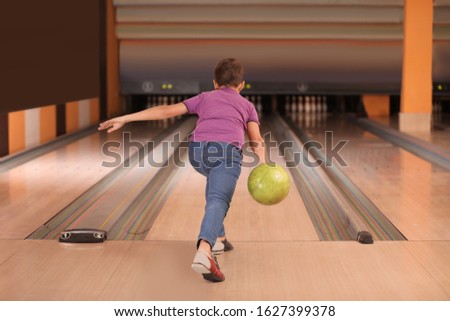 Preteen boy throwing ball at bowling club