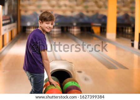 Preteen boy near balls in bowling club. Space for text