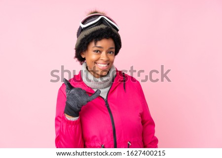 African american skier woman with snowboarding glasses over isolated pink background making phone gesture