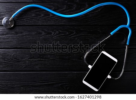 Smartphone and stethoscope on wooden rustic background. Top view. Nobody