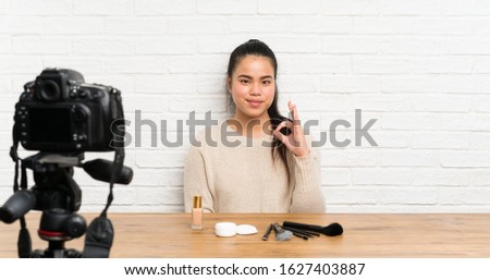 Young blogger Asian girl recording a video tutorial showing an ok sign with fingers