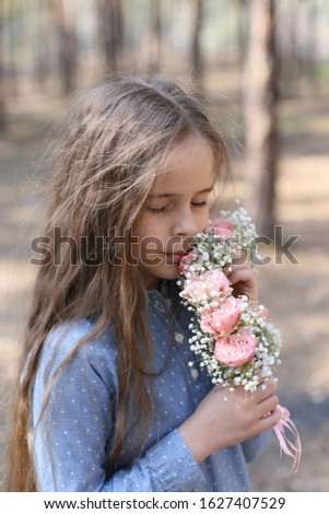 girl with long dark hair stands with a floral wreath in her hands on a forest background