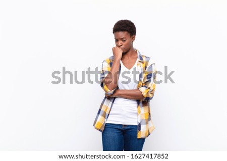 young pretty black womanfeeling serious, thoughtful and concerned, staring sideways with hand pressed against chin