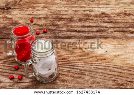 Love concept for Valentines day or mothers day. Red felt heart, glass jar, roses, ribbons. Old wooden boards background, copy space
