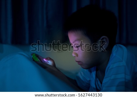 asian chinese boy playing smartphone on bed, kid use phone and play game, addicted game and cartoon, 
