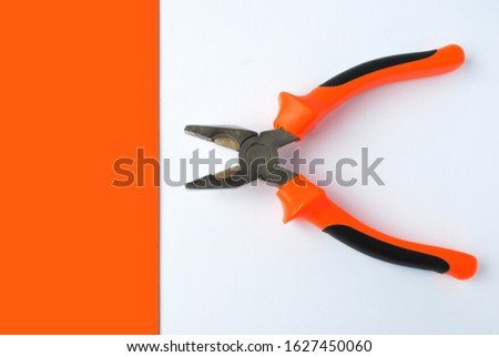 work tools pliers with an orange handle on a white background and a bright orange background. for advertising banners flyers screensavers labels and more