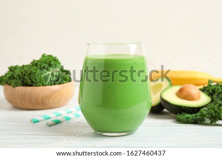 Tasty fresh kale smoothie on white wooden table