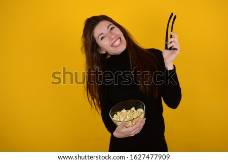 cheerful woman in 3d glasses with popcorn in hands on an isolated yellow background