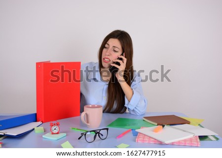 woman sitting at a table in the office and talking on the business phone