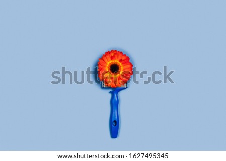 Holiday card with an abstract of one gerbera flower and a blue construction brush.