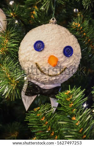 Christmas toy snowman with butterfly hanging on branch, snowman with eyes from buttons