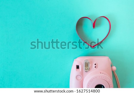 flat lay of valentines creative with polaroid camera and ribbon shaped heart on pastel background, copy space.
