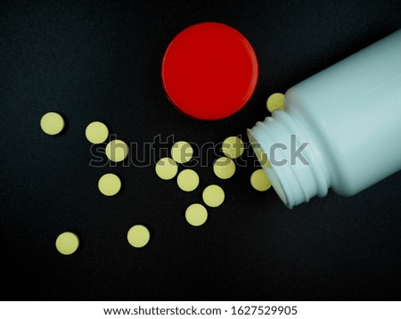  yellow pills in white bottle isolated on the background.